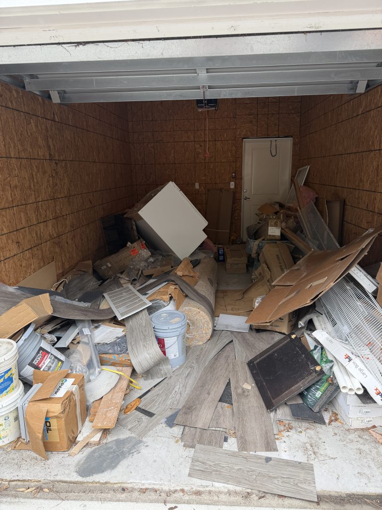 Cluttered garage with boxes and stored items before a Hoard Haulers pickup